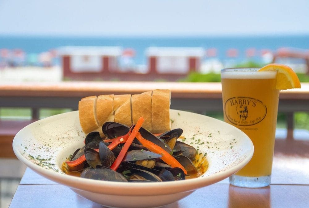 Image of clams in bowl with glass of beer on table.